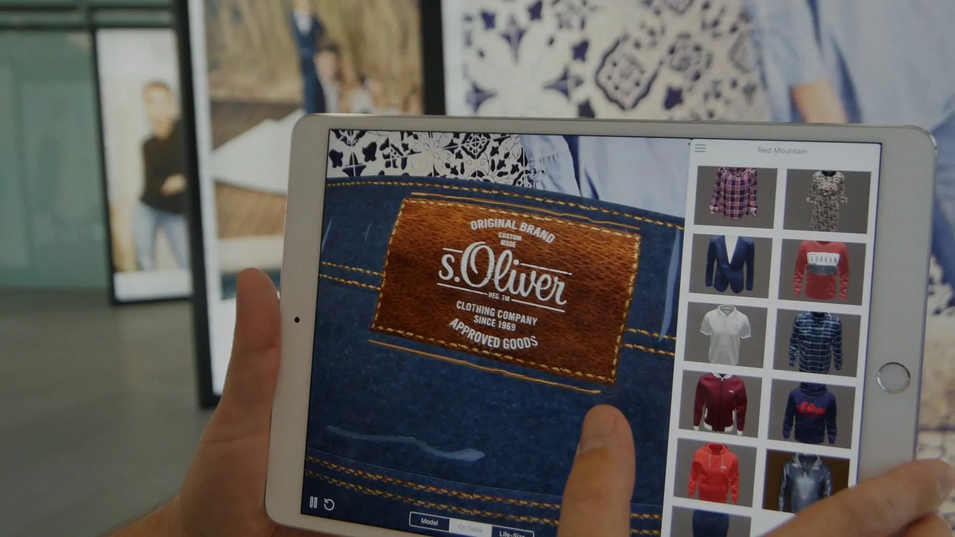 iPad-App zeigt Nahansicht des s.Oliver Jeans-Labels mit Schriftzug „Original Brand – Clothing Company Since 1969" und Kollektionsgrid
