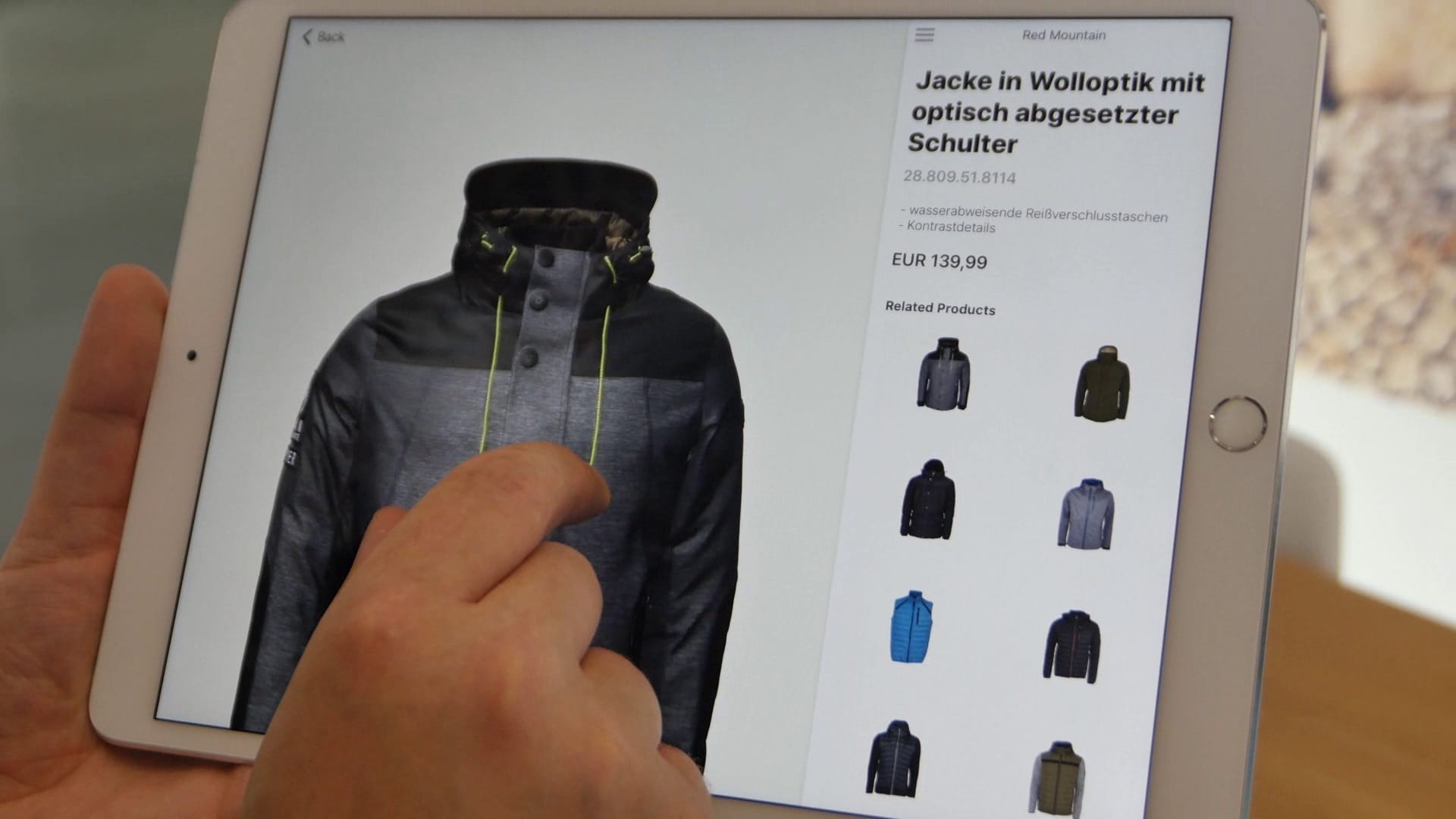 iPad-App zeigt Jacke in Wolloptik mit Artikelnummer, Preis und verwandten Produkten – Touch-Interaktion sichtbar
